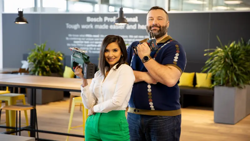 Two associates of Bosch Power Tools pose in the office each with one of our power tools in their hands.