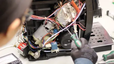 Nahaufnahme, wie eine Frau eine defekte Kaffeemaschine repariert.